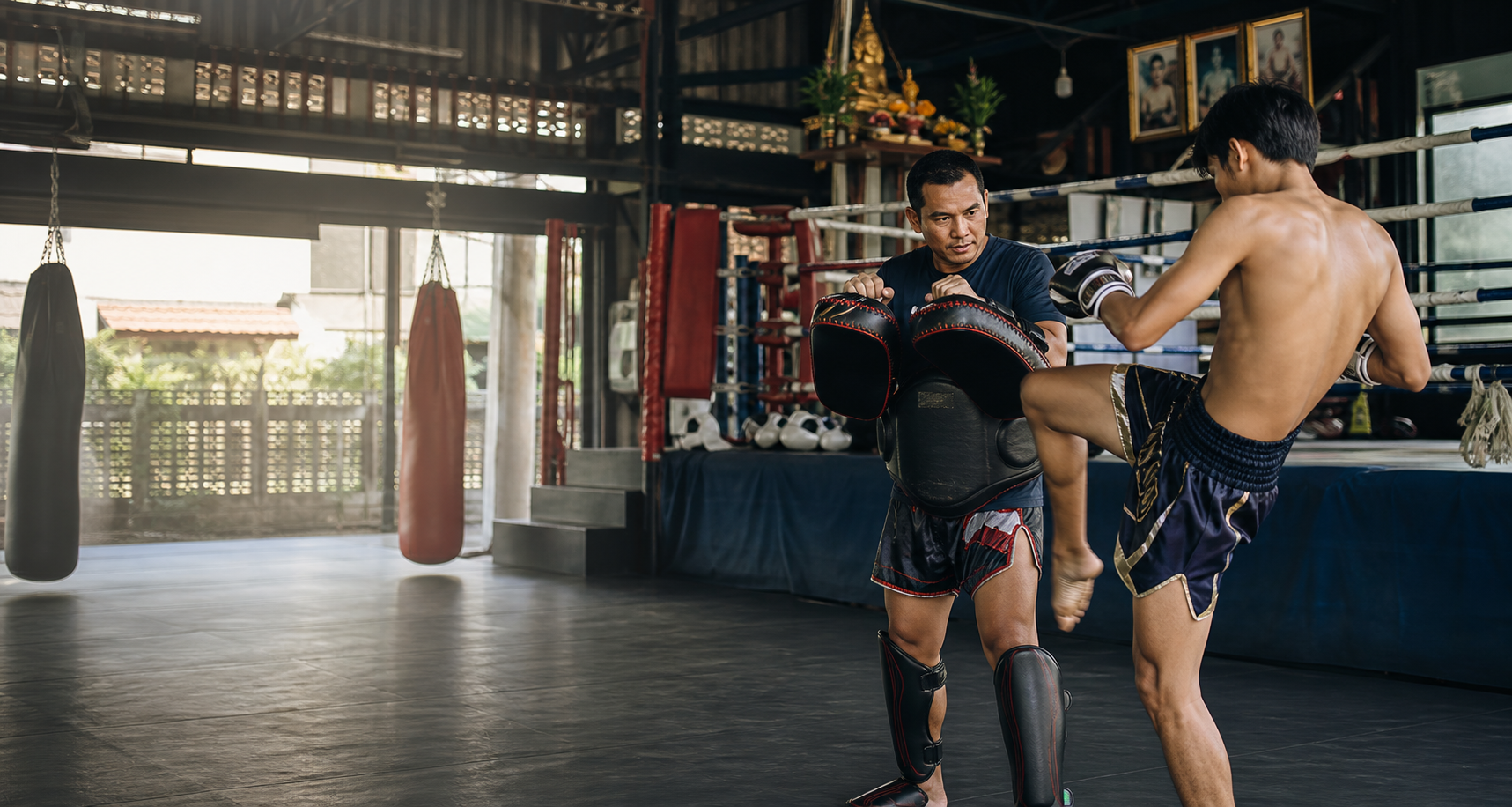 Muay Thai coach holding pads in a Bangkok training gym